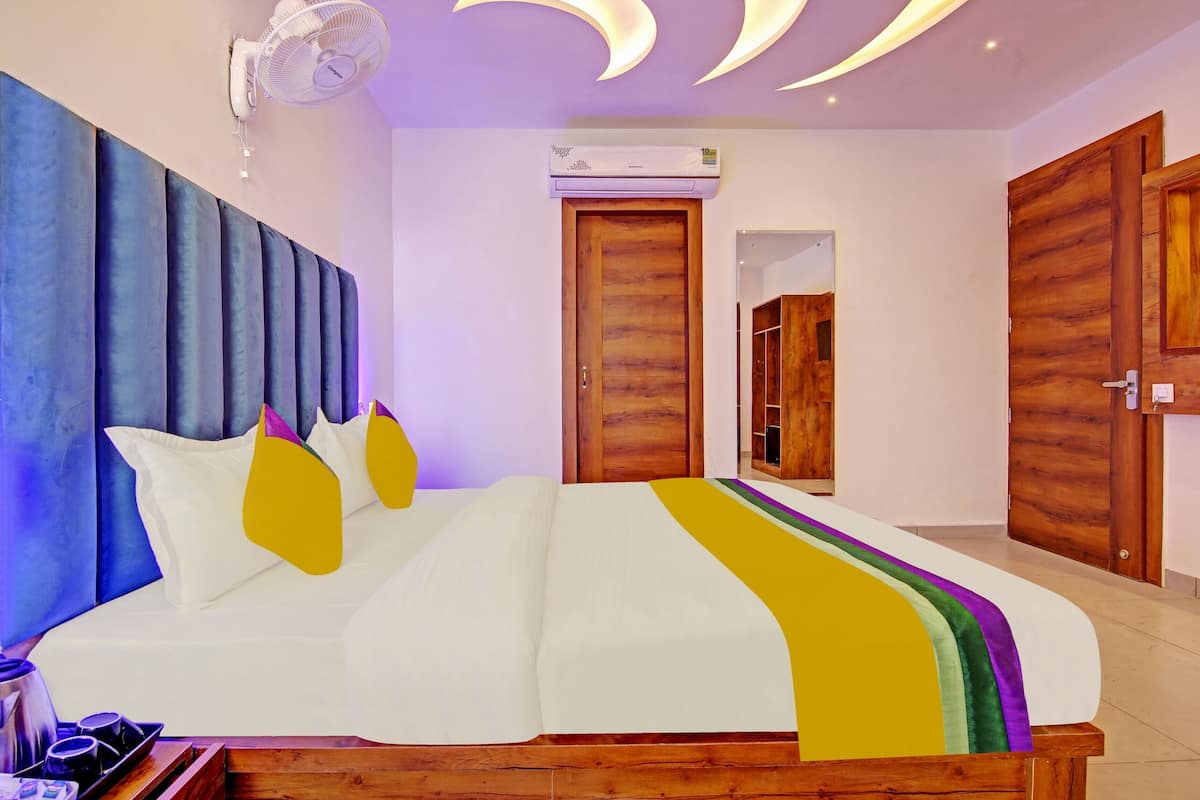 A bedroom with a bed, bedside tables, a wall-mounted air conditioner, and wooden doors.