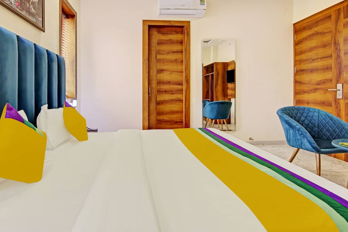 A hotel room with a bed, a chair, a wooden door, and a mirror.