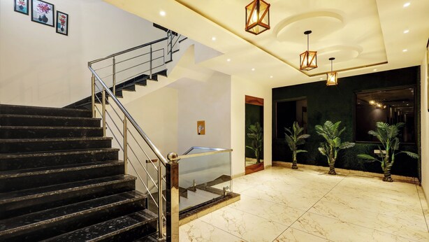 A modern hotel lobby with a marble floor, a glass elevator, and a staircase with metal railings. - Itsy Hotels Vedansh (Ludhiana)