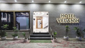 The exterior of Hotel Vedansh with a modern entrance, a staircase leading to the entrance, and potted plants at the base. - Itsy Hotels Vedansh (Ludhiana)
