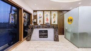 A hotel reception area with a marble counter, framed artwork, and a check-in/out sign. - Itsy Hotels Vedansh (Ludhiana)