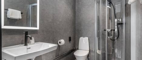 Un baño moderno con ducha acristalada, lavamanos blanco y un inodoro.