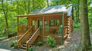 A wooden cabin with a porch and stairs, surrounded by trees. - Great Location 4 minutes from Patoka Lake Entrance with Hot Tub! (Birdseye)
