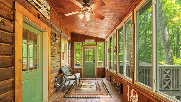 A wooden cabin with a porch, a ceiling fan, and a green door. - Great Location 4 minutes from Patoka Lake Entrance with Hot Tub! (Birdseye)