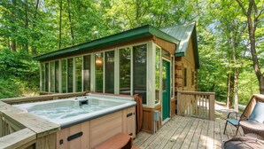 A wooden deck with a hot tub, a covered seating area, and a view of the forest. - Great Location 4 minutes from Patoka Lake Entrance with Hot Tub! (Birdseye)