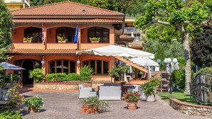 A two-story building with a tiled roof, outdoor seating area, and a staircase leading to the upper level. - House Geranio  in Tuscany (LUCCA) with Pool, garden and spectacular sea view  (Toscana)