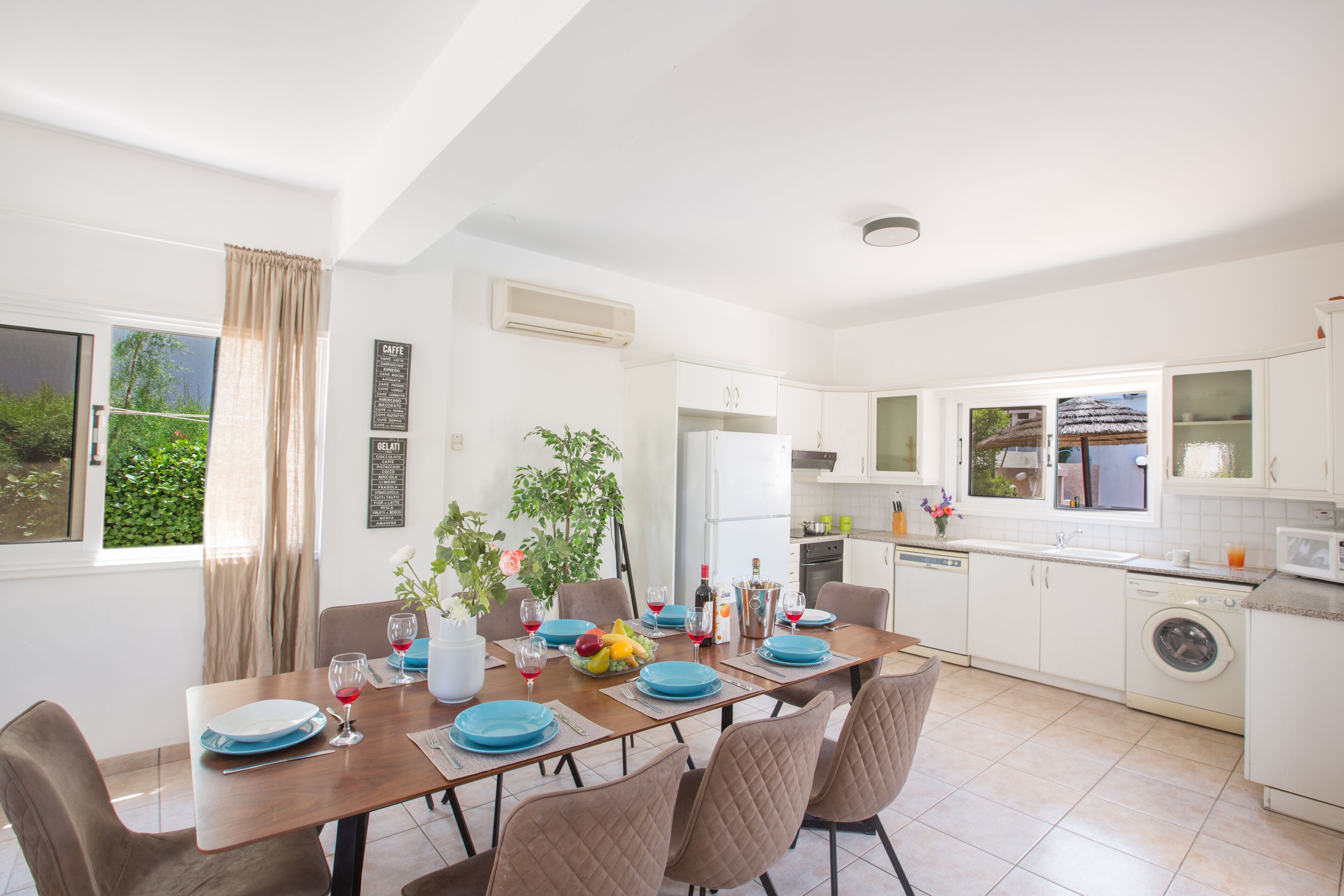 A modern kitchen with white cabinets, a built-in dishwasher, and a dining area with a table set for four.