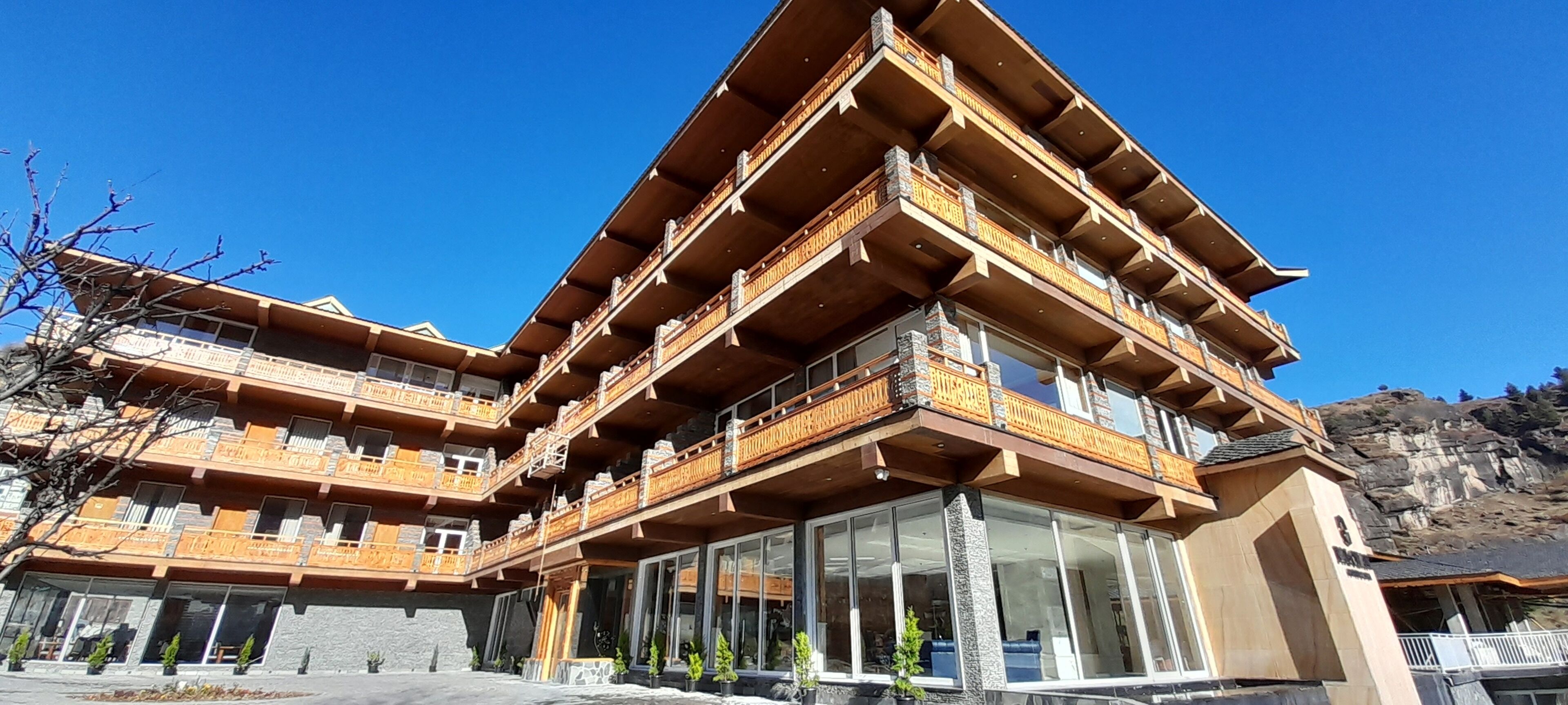 A multi-story hotel with wooden balconies and large windows.