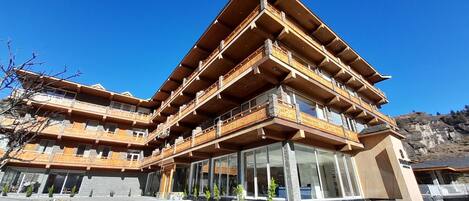 A multi-story hotel with wooden balconies and large windows.