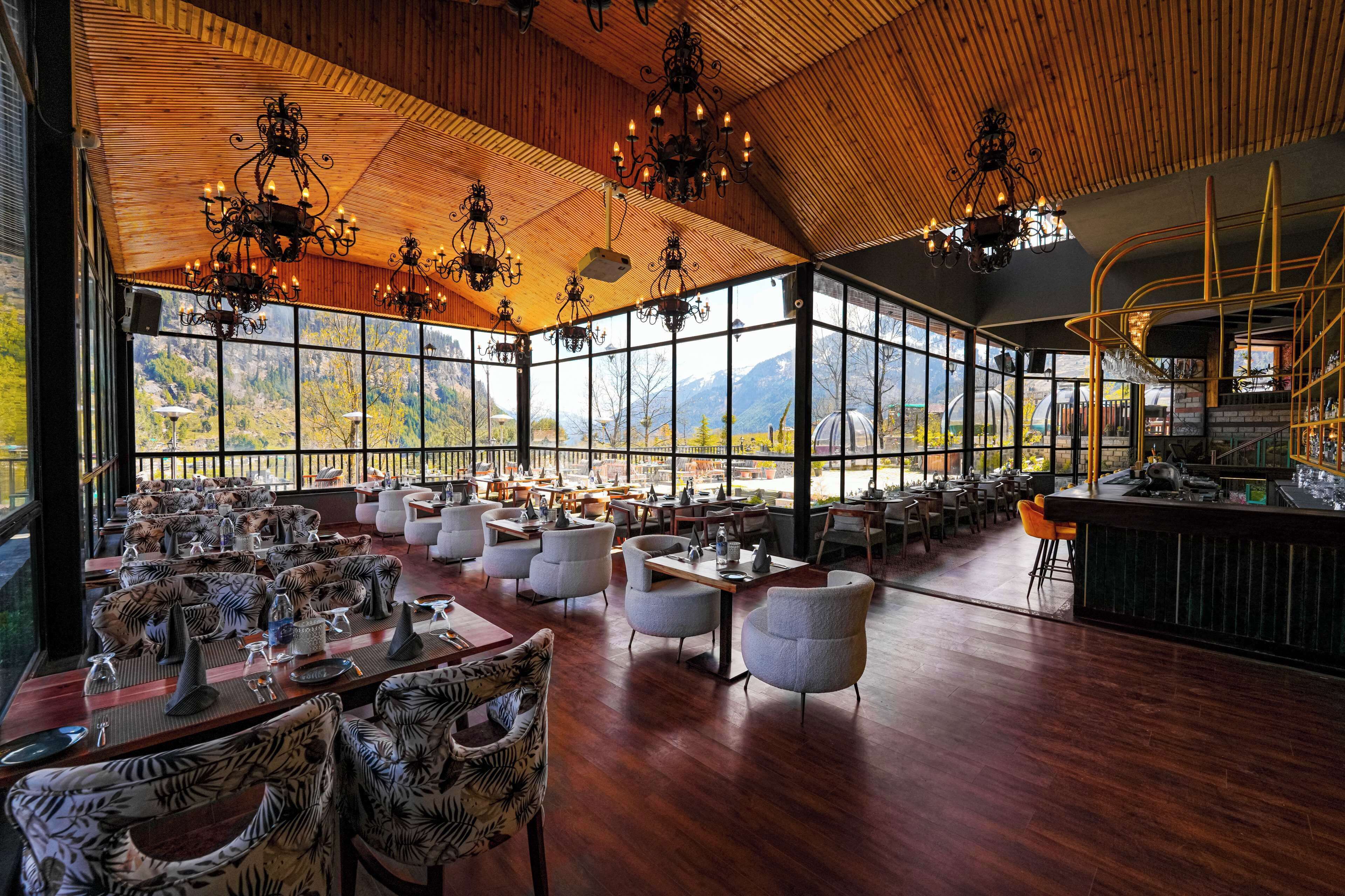 A spacious restaurant with high ceilings, large windows, and a variety of seating arrangements.