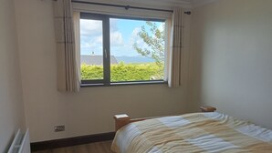 Un dormitorio con un ventanal grande, una cama y un radiador.