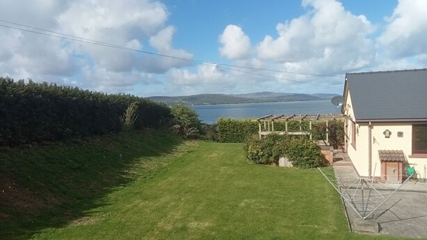 Una casa con vista a un lago y colinas al fondo.