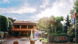 A hotel entrance with a sign reading "VERDE," outdoor seating, and a well-maintained garden. - House Girasole in the country with Pool, garden and spectacular sea view  (Toscana)