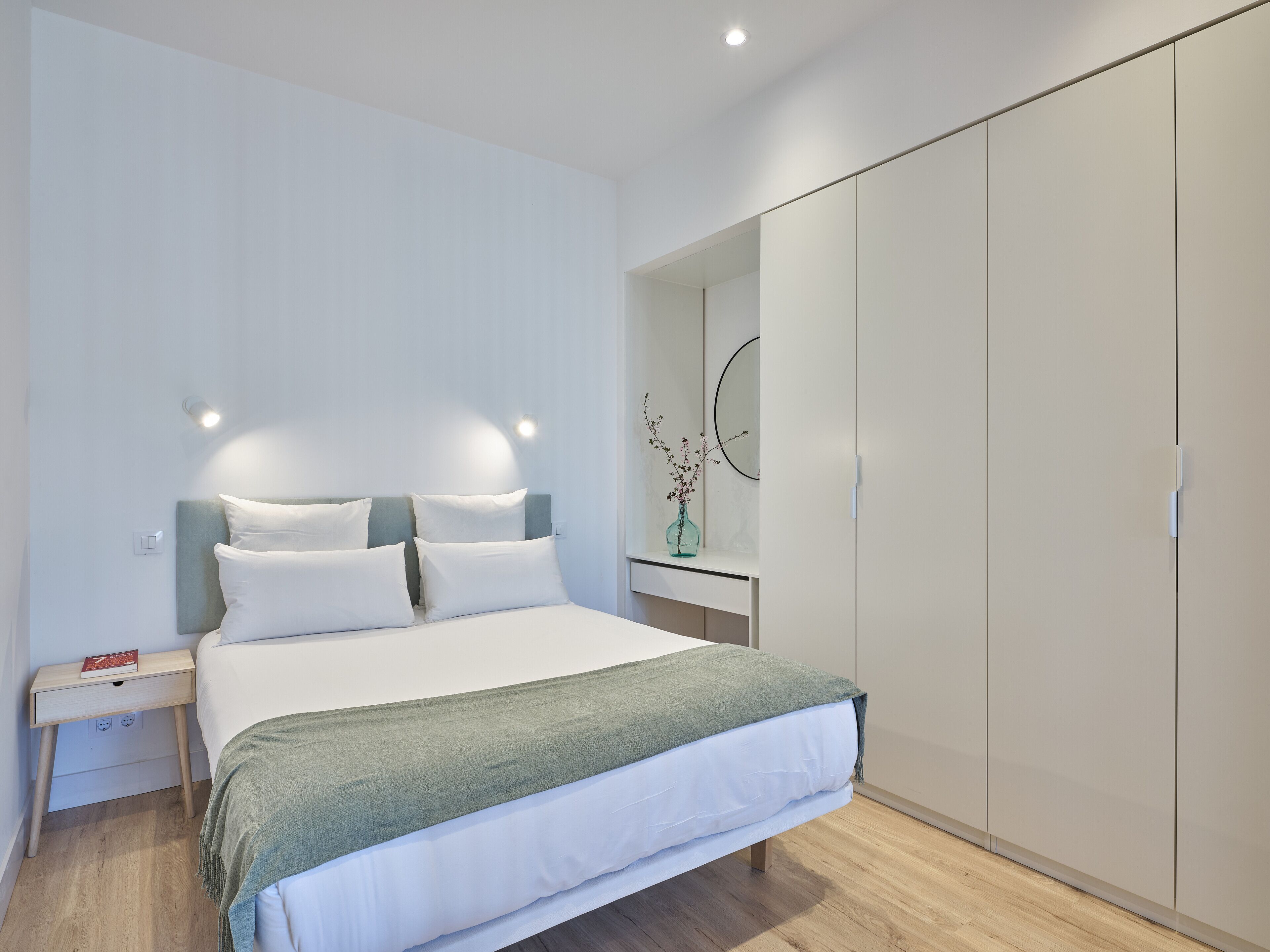 A modern bedroom with a bed, bedside table, and wardrobe.