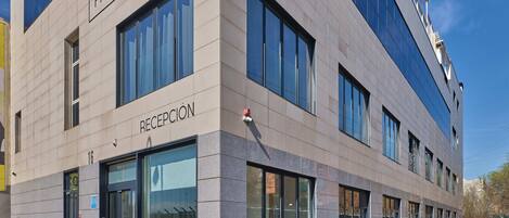A modern hotel with a reception area, large windows, and a clean, tiled facade.