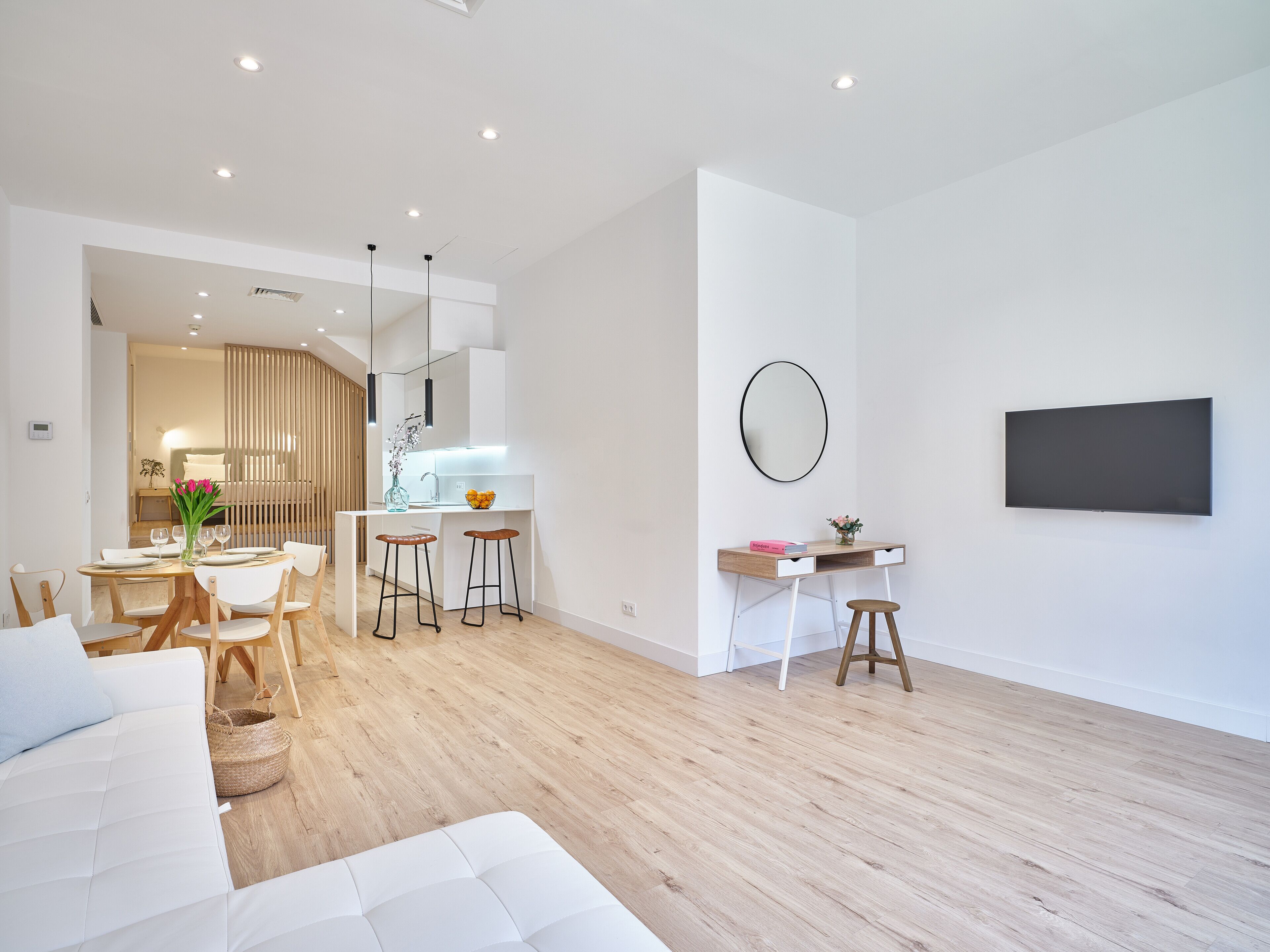 A modern, well-lit living area with a dining space, a kitchen, and a workspace.