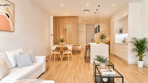 Ein modernes Wohnzimmer mit Sofa, Esstisch und Küchenbereich.