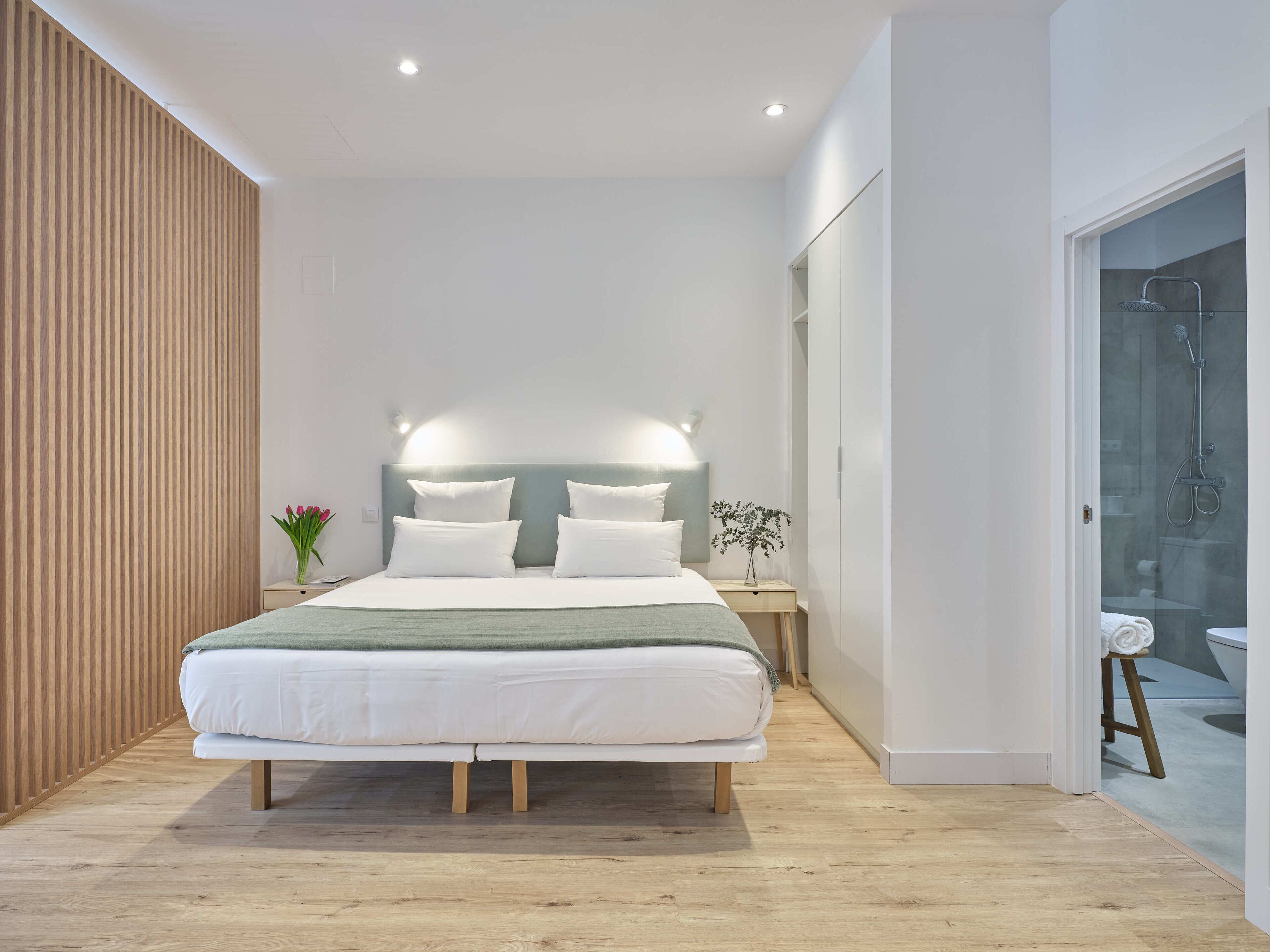 Un dormitorio moderno con una cama grande, mesitas de noche y un cabina de ducha de vidrio.