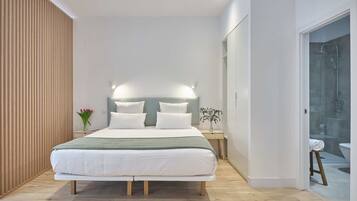Un dormitorio moderno con una cama grande, mesitas de noche y un cabina de ducha de vidrio.