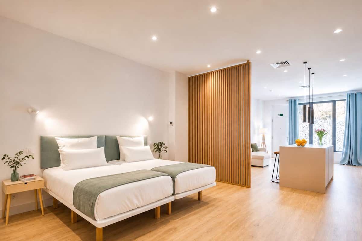 A modern hotel room with a large bed, bedside tables, a desk, and a view of the city.