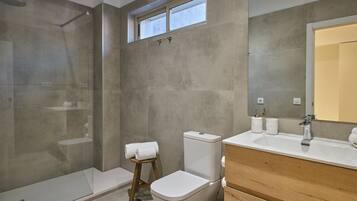 Un baño moderno con ducha, inodoro y tocador.
