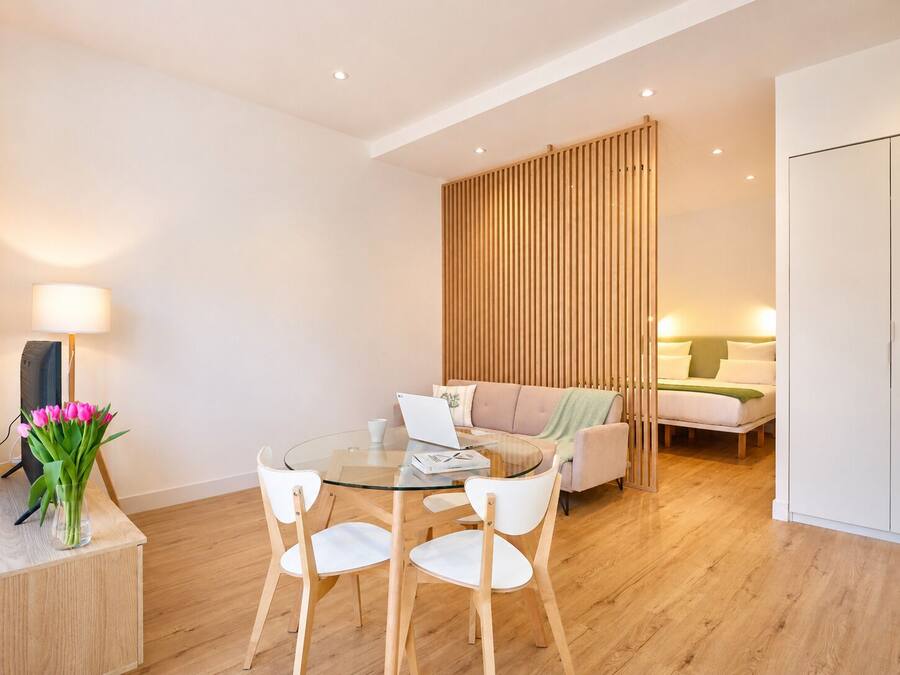 Una sala de estar moderna con una mesa de comedor de cristal, sillas blancas, un sofá y una cama.