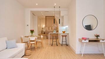 Een moderne woonkamer met een bank, een eettafel en een keuken met krukken.