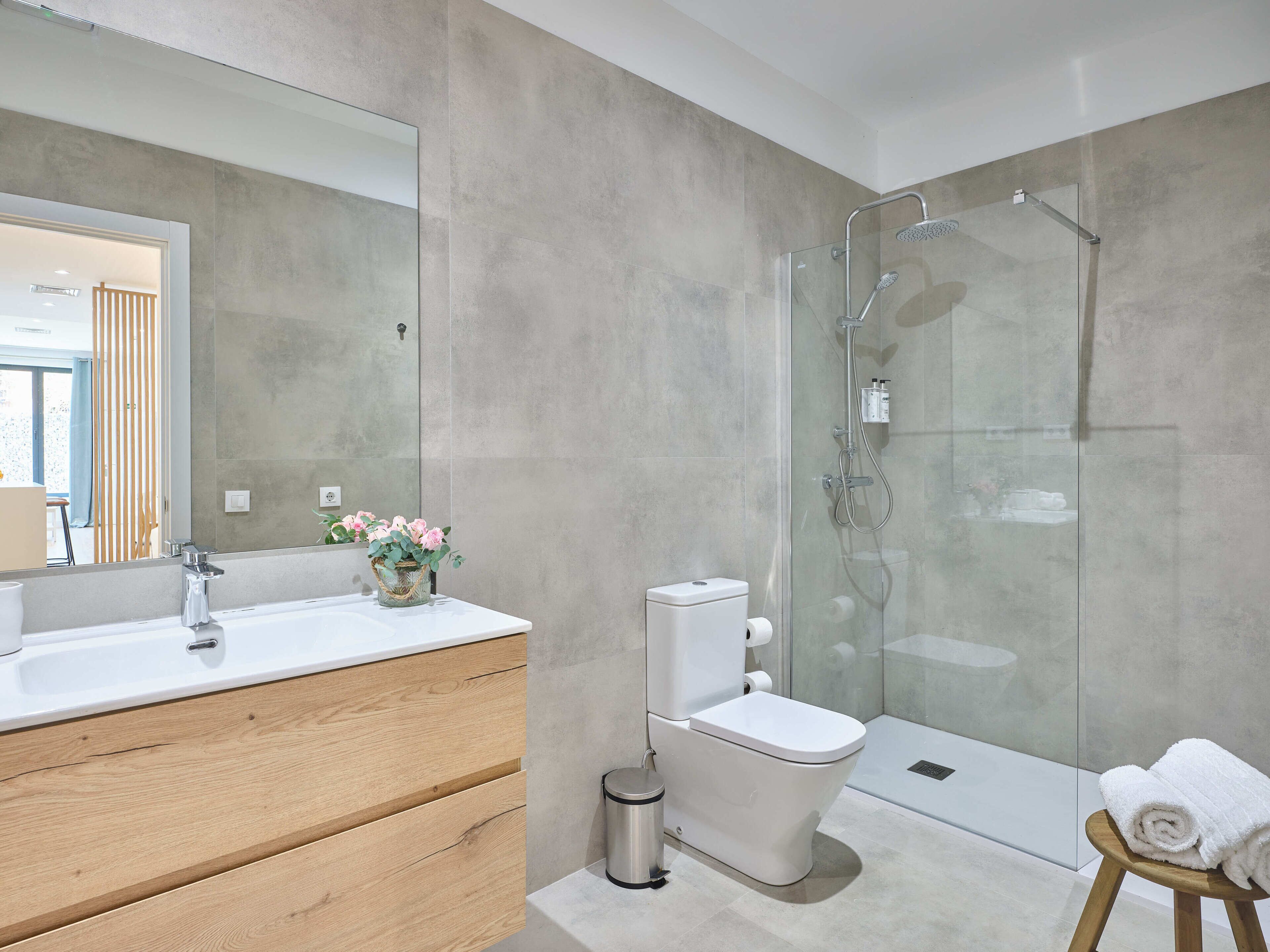 Ein modernes Badezimmer mit Duschkabine aus Glas, einem Holzwaschtisch und einer Toilette.