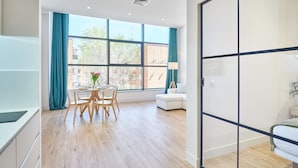 Ein modernes Zimmer mit Essbereich, einem Bett und Blick ins Freie.