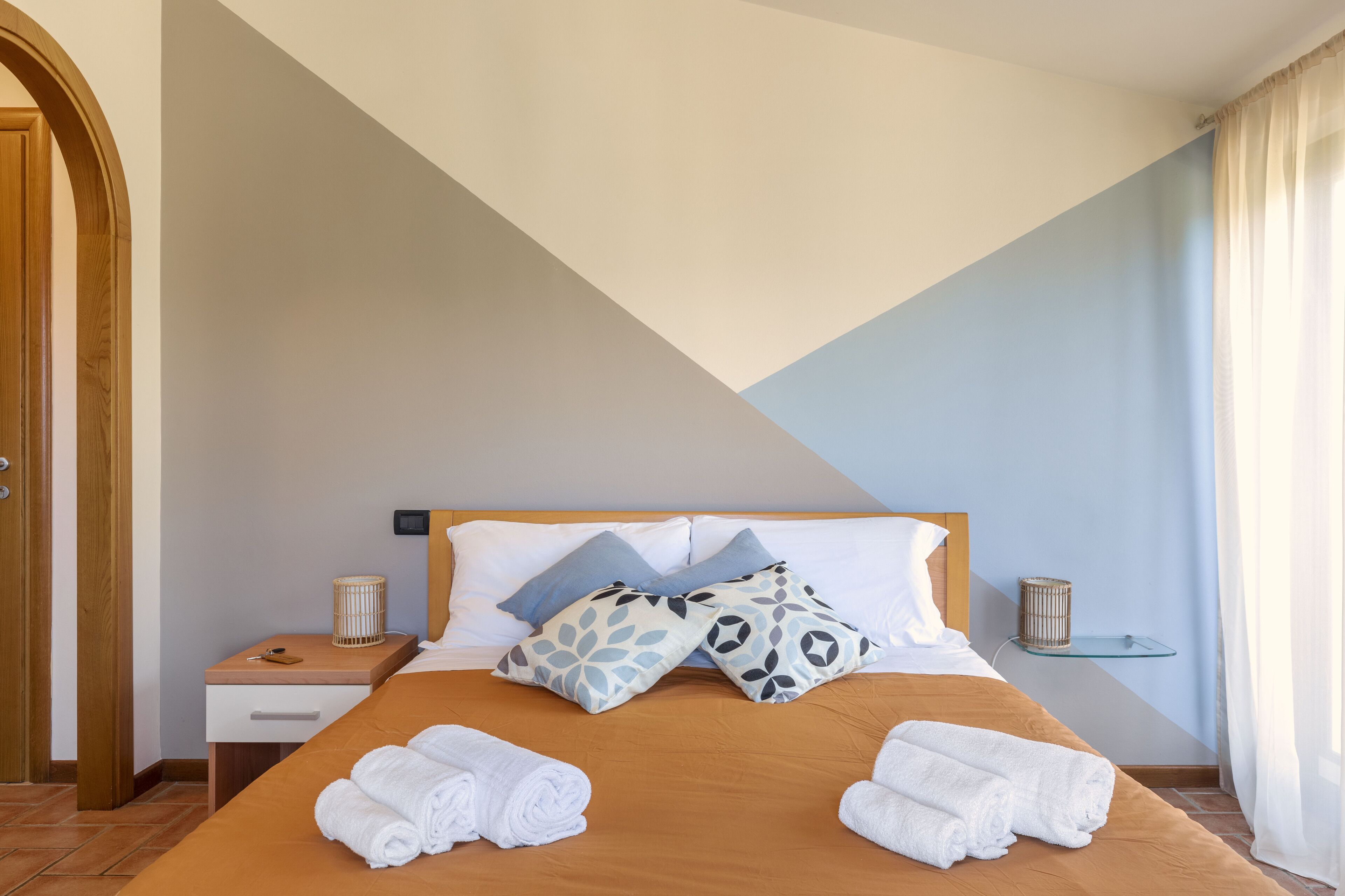 Une chambre d’hôtel avec un lit, des oreillers, une table de chevet, une lampe et des serviettes.