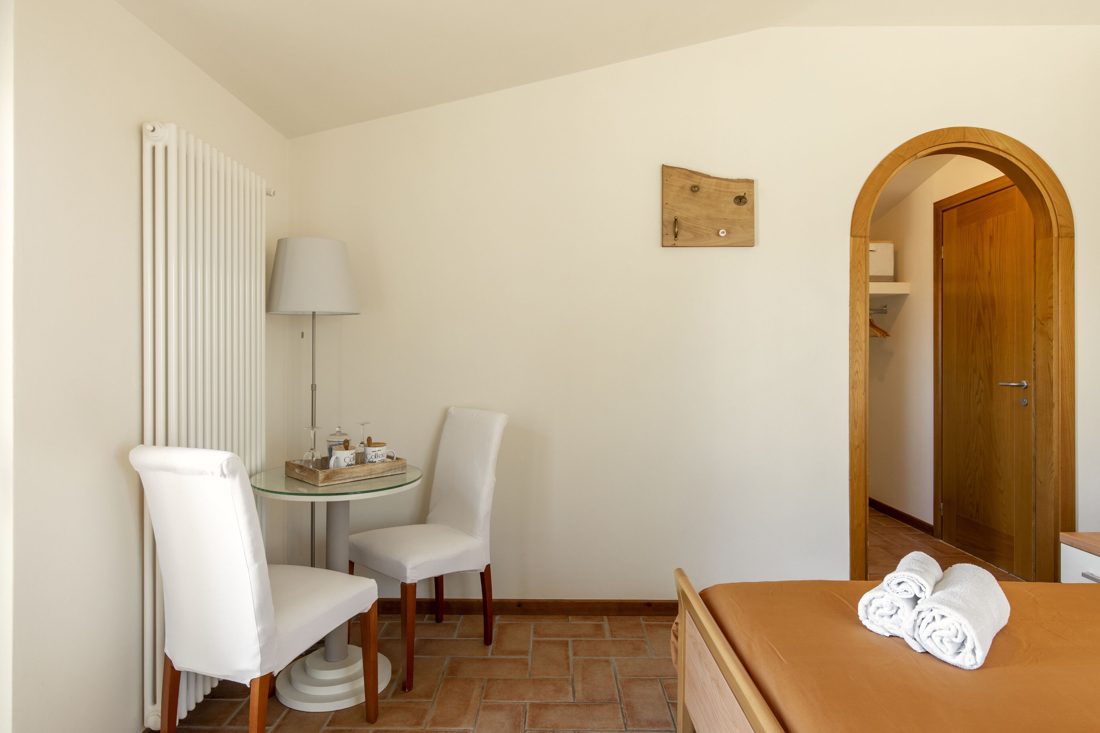 Habitación de hotel con cama, una silla, una mesita, una lámpara y una puerta de madera.