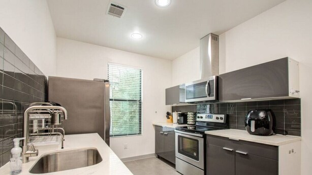 A modern kitchen with stainless steel appliances, a built-in oven, and a microwave.