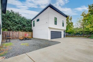 A modern two-story house with a garage, a gravel driveway, and a wooden fence.
