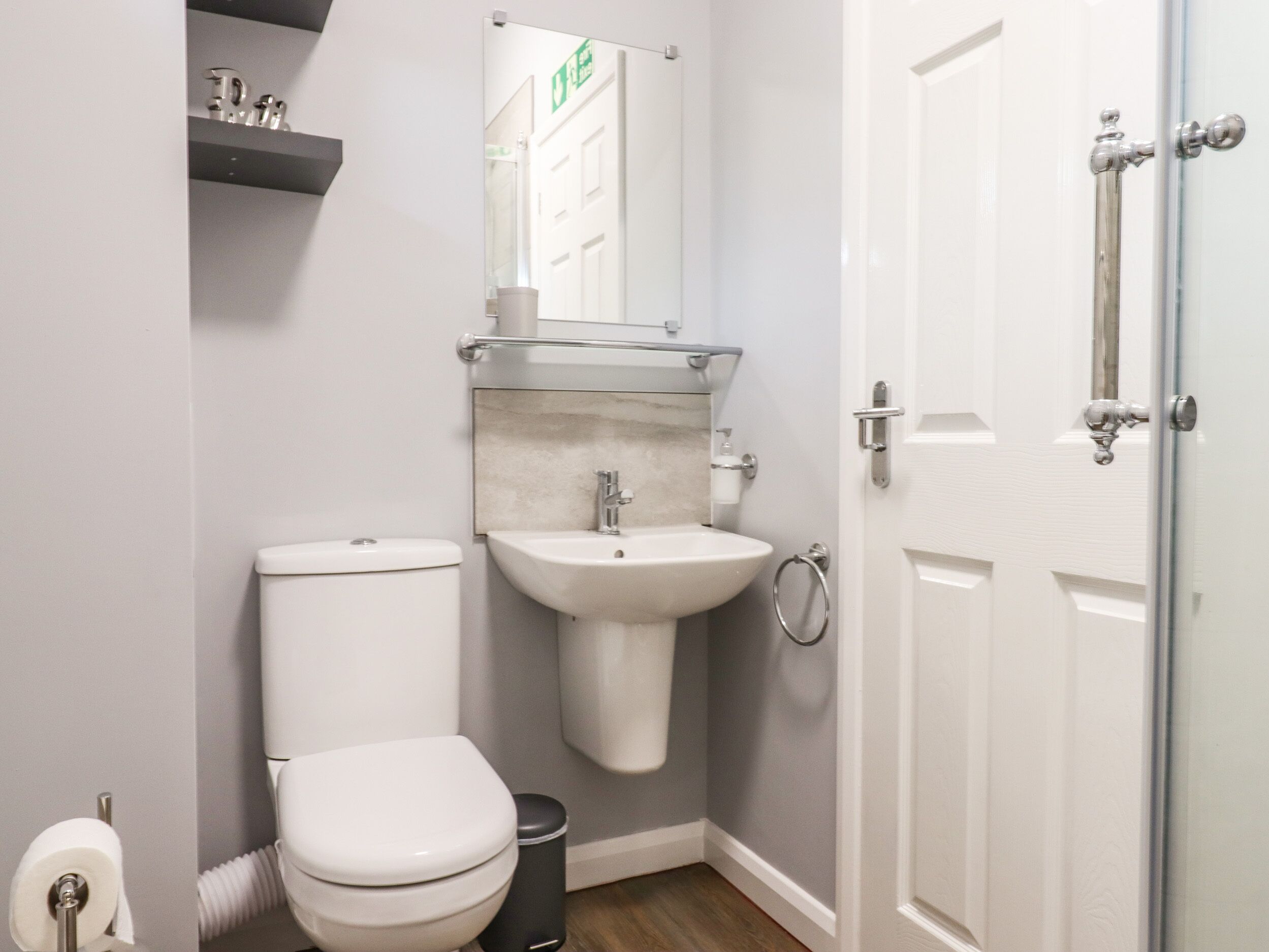 Une petite salle de bain comprenant des toilettes, un lavabo et une porte de douche en verre.