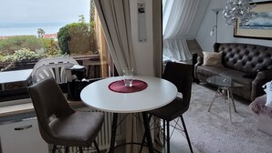 Ein Zimmer mit einem runden Tisch, zwei Stühlen, einer Couch und Meerblick.