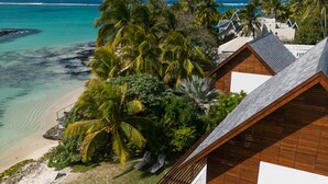 Un resort con vista a la playa, palmeras y un cielo azul despejado.