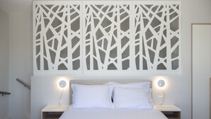 Une chambre à coucher comprenant un lit, deux tables de chevet et un luminaire fixé au mur.