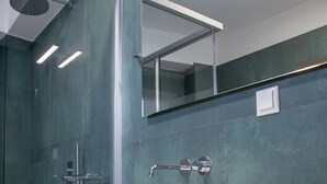 Une salle de bain moderne avec un grand lavabo blanc, une douche en verre et un miroir au-dessus du lavabo.