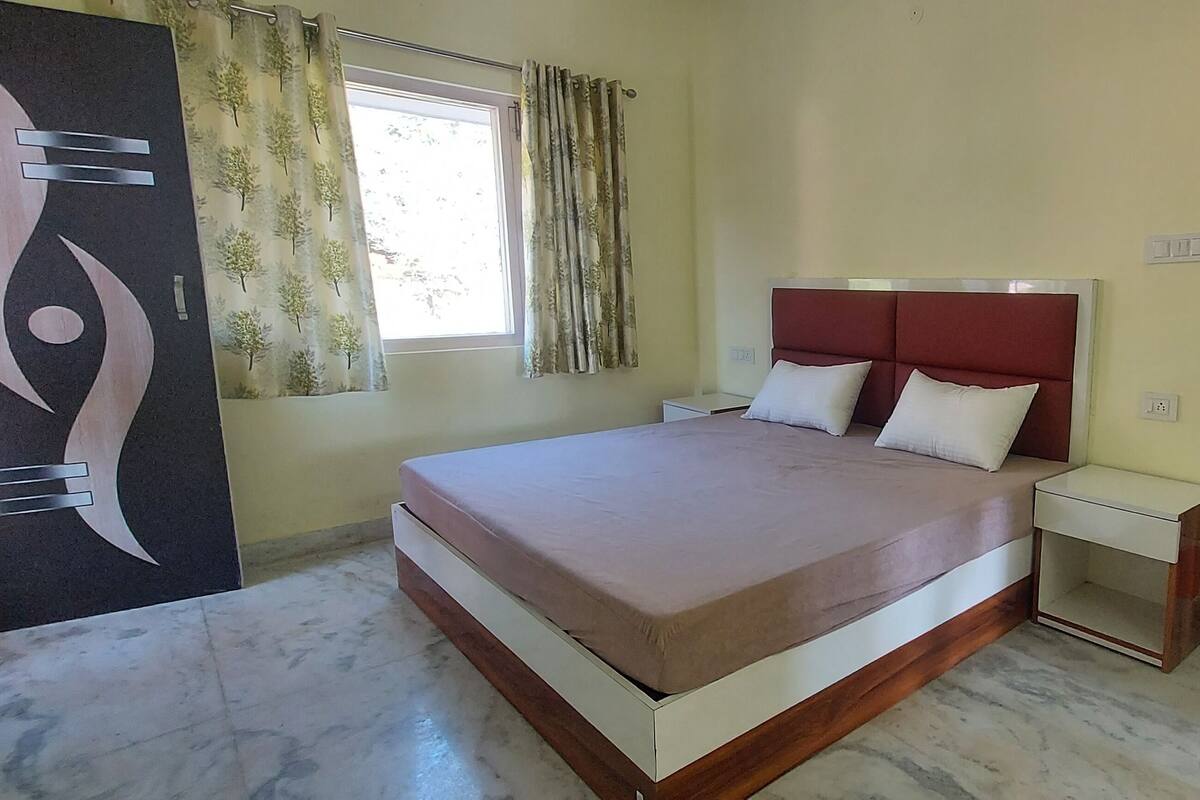 A bedroom with a bed, nightstands, a wardrobe, and a large abstract artwork on the wall.