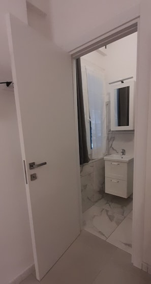 Une salle de bain avec un lavabo blanc, un miroir et un sol carrelé.