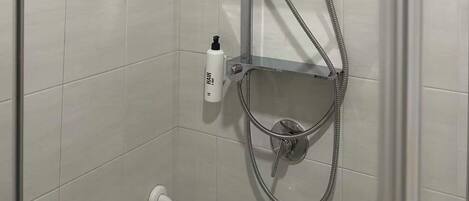 A shower with a handheld showerhead, a fixed showerhead, and a handheld shower hose.