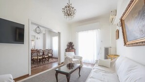A living room with a sofa, a coffee table, a TV, and a chandelier. - Classic Athenean Apartment at Acropolis Museum & Metro (Athens)