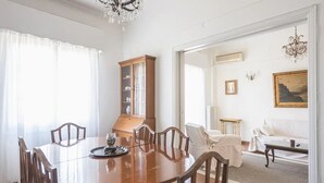 A dining area with a wooden table, chairs, a cabinet, and a view into a living room with a sofa and a painting. - Classic Athenean Apartment at Acropolis Museum & Metro (Athens)