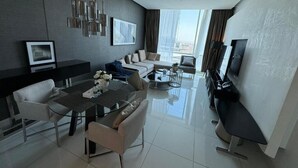 A modern living room with a sofa, a dining table, and a TV. - DAMAC Towers Riyadh داماك تاورز الرياض (Riyadh)
