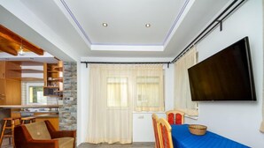 Ein kompakter Wohnbereich mit Küchenzeile, Essbereich und Wand-Fernseher.