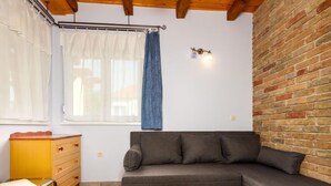 Ein gemütliches Zimmer mit grauem Sofa, einem Holzschrank und einer Backsteinwand.