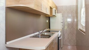 A modern kitchen with wooden cabinets, a stainless steel sink, and a microwave. - Vacation home Marie by Interhome (Balatonmariafurdo)