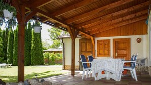 Un patio couvert avec une table et des chaises, un chemin en pierre et une porte en bois.