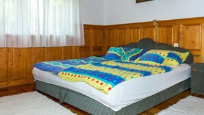 A bedroom with a wooden headboard, a colorful bedspread, and a painting on the wall. - Vacation home Marie by Interhome (Balatonmariafurdo)