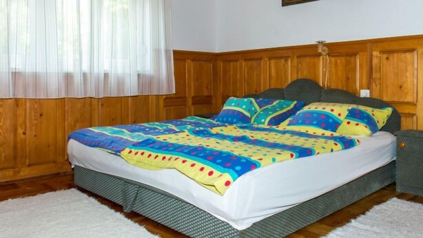 Une chambre à coucher avec une tête de lit en bois, une couvre-lit aux couleurs vives et un tableau accroché au mur.